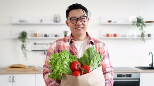 Smiling Man Holding Bag of Fresh Vegetables Indoors