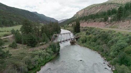 Drone view of a railroad bridge going over a river in Colorado's mountains