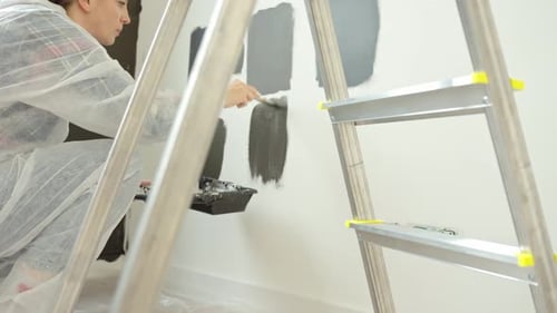 Woman Painting Gray Swatches on White Wall