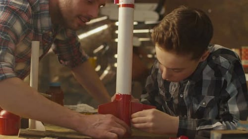 Father and son are modeling a toy rocket in a garage at home.