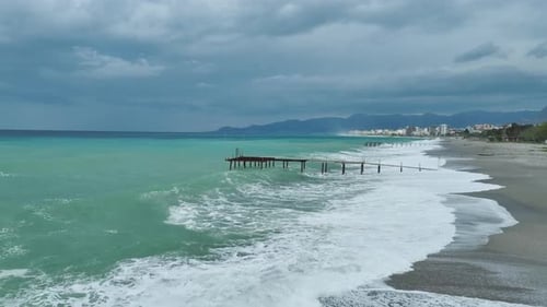 Aerial Video of Powerful Ocean Swell Crashing Into Rocky Shore With White Foam Surrounding Boulders