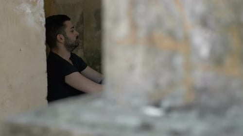 Man with Beard Sitting Against a Wall