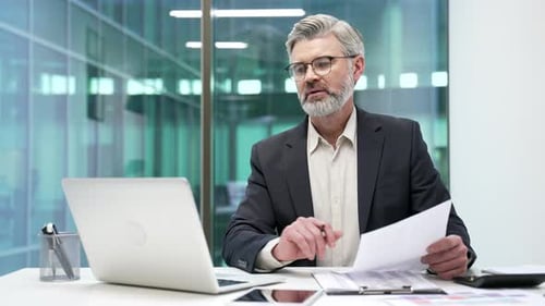 Confident Businessman Working at Desk in Modern Office