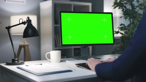 Man at Desk with Green Screen Monitor