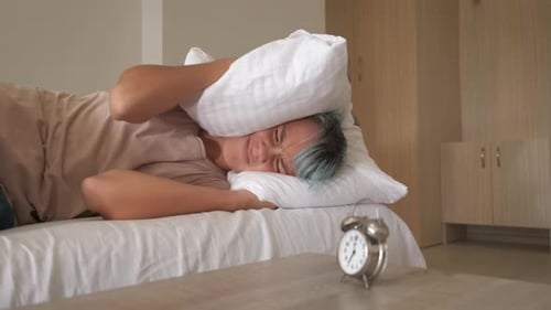 Person Lying in Bed with Alarm Clock