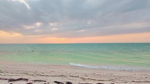 Sunset over calm turquoise ocean at Punta Cocos Beach in Holbox Island, Mexico