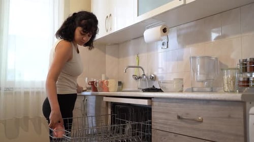 Woman loading glasses into the dishwasher 4K