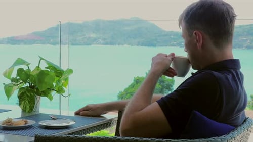 In a Hotel Cafe Terrace a Man Relax Looking at Sea View