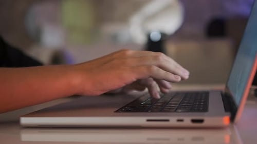 Weibliche Hände, die zu Hause bei warmem Licht auf dem Laptop tippen, Telearbeit und Online-Kommunikation schreiben
