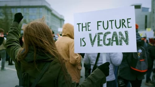 Une femme tient une pancarte L'avenir est une bannière de démonstration de véganisme végétalien pour les droits des animaux