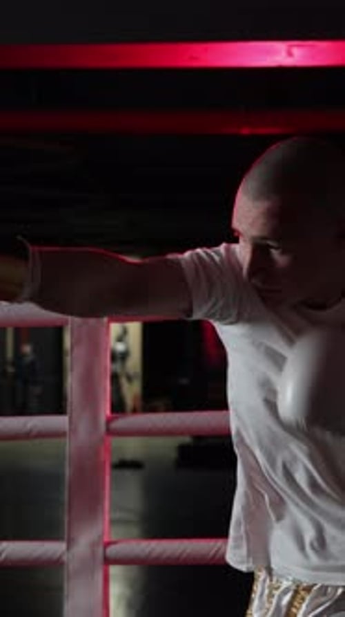 Professionelles männliches Boxertraining in einem dunklen Boxring