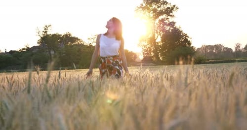 On a sunny day, a woman is walking along a wheat field with a white dress, in a straw hat on a nat