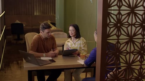 Business Team Meeting at Table with Laptop and Tablet