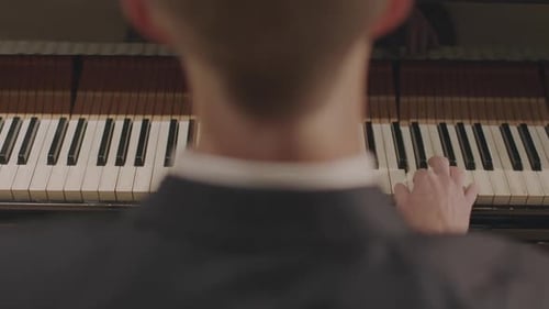 Man Plays Piano in a Dimly Lit Room