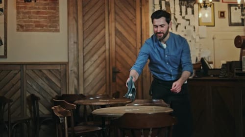 Bartender Wiping Tables of Vintage Bistro While Smiling and Looking at Camera