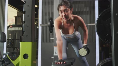 Asian Woman Lifting Dumbbell on Bench in Fitness Gym Happy Young Female Doing Strength Training