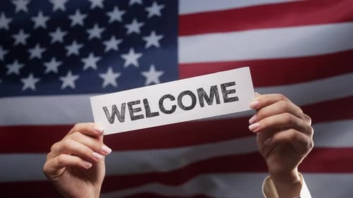 Hands Holding Welcome Sign Over American Flag
