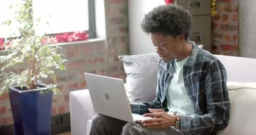 Young Adult Using Laptop on Sofa Indoors