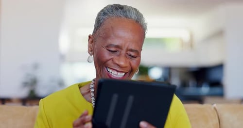 Senior Woman Smiling While Using a Tablet Indoors
