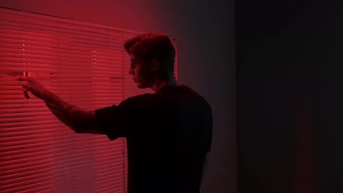 Portrait of Male Model in Dark Studio Young Man in Glasses Standing Near Window with Red Light