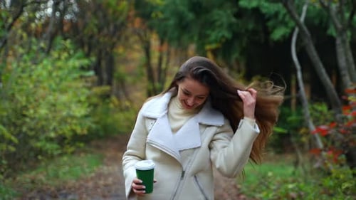 Pretty lady walking by in autumn street. Attractive young woman walking down the park.
