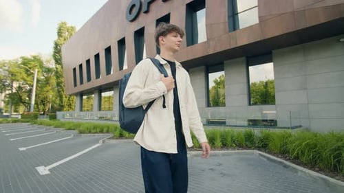 Teen Boy with Backpack Walking Alone Outside a Modern School Building