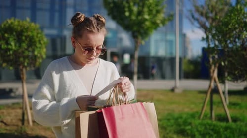Woman Reading Receipt with Shopping Bags Outside