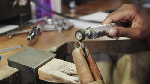 Biracial female worker shaping ring using handcraft tools in workshop in slow motion