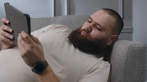 Man Relaxes on Couch with Tablet Indoors