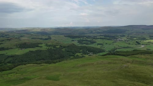 Aerial shot looking over the hilly countryside, looking down from a hill, bright sunny day.