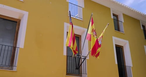 Flags Waving on Yellow Building Exterior in City