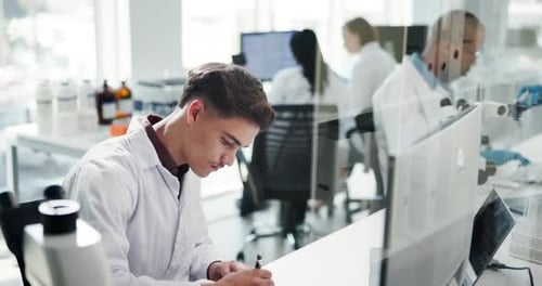 Young Man Writing in a Bright Laboratory