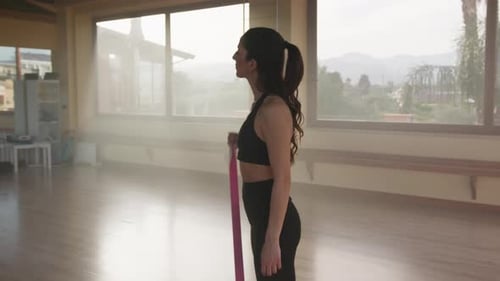 Athletic Woman Exercising with Resistance Band in Studio