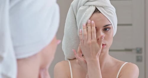Woman Applying Cream in Mirror with Towel