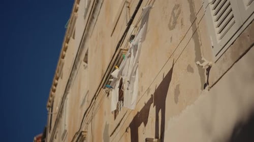 Laundry hanging from an old building in a sunlit neighborhood of Dubrovnik old city