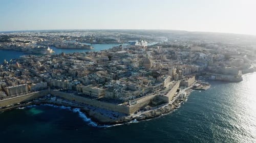 Aerial orbiting right wide shot of Valletta old town during sunset with bright sky, Malta drone