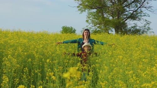 Happy Mother and Child Run on Agricultural Land with Rapeseed