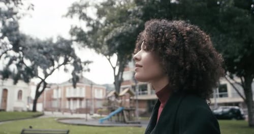 A girl in a suit with curly hair walks looking around in the city of Bogota, Colombia