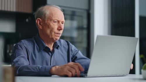 Senior Man Working at Laptop in Home