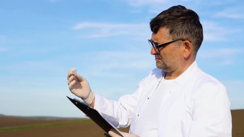 Laboratory Worker Holding Professional Glassware and Testing Corn Grains Before Harvest in the Field