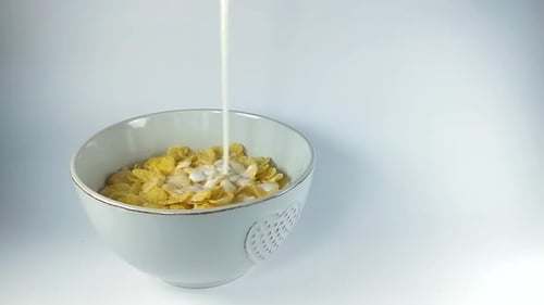 Pouring milk on corn flakes in a ceramic bowl, ISOLATED, STILL