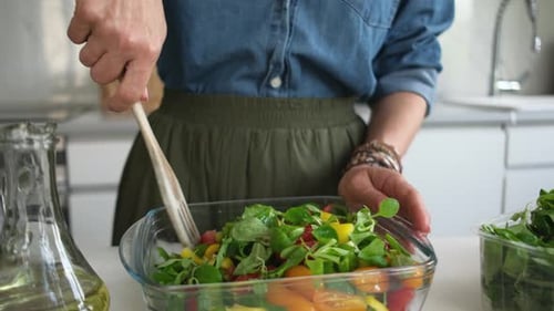 Woman Mixing Salad in Kitchen with Wooden Utensil