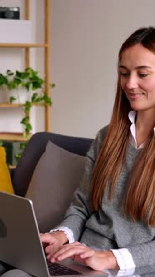 Happy Woman Using Laptop Sitting on Sofa