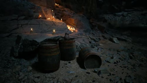 Candles Illuminate a Rocky Cave with Ancient Barrels Resting Nearby