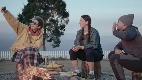 Friends Gather Around Campfire In Rural Setting