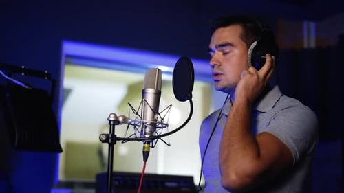 Male Caucasian singer performing song in the modern studio.