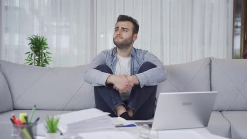 Worried Young Man Sitting on Sofa Indoors