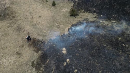 A fireman extinguishes a fire. Burning field. Wildfire in the mountains. Forest fire.