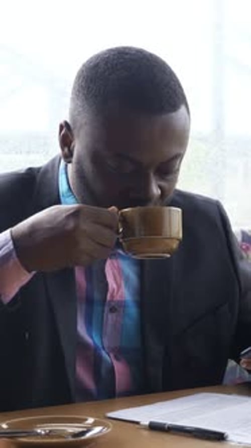 Ein Profi entspannt sich mit einem warmen Getränk. Eine Person untersucht die Unterlagen in aller Ruhe und genießt dabei heißen Kaffee