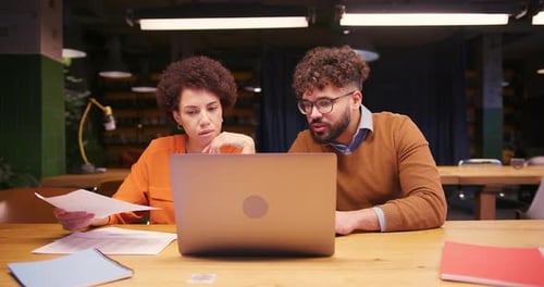 Professional Colleagues Analyzing Documents Using Laptop Working in Modern Office
